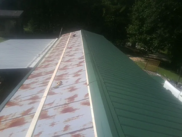 Old rusted panels beside newly installed green metal roofing — Wind Damage Roof Repair by Roofing Brothers in Ellaville