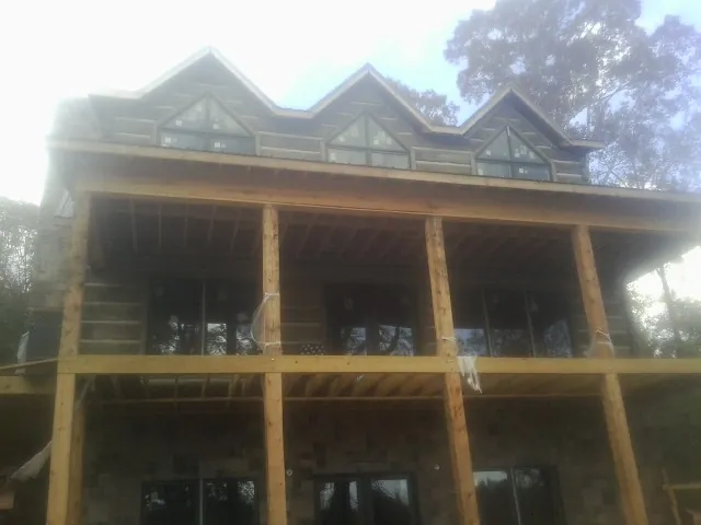 Dormers and porch framing on a large log home under construction — Roof Coating work by our crew in Ellaville