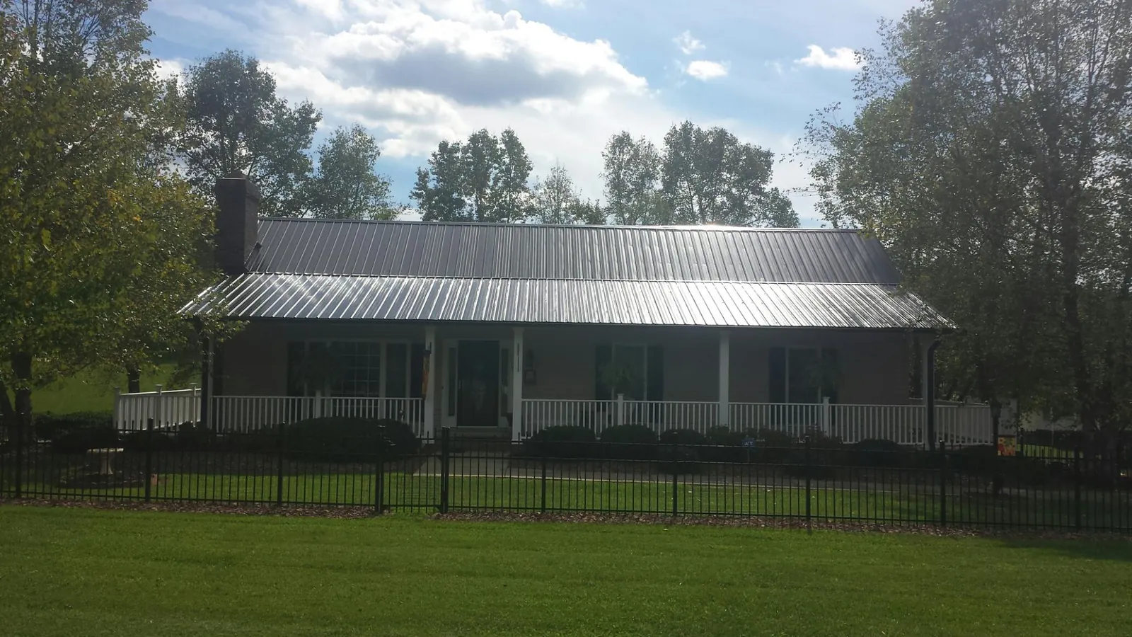 Gray metal roof on a brick ranch with a full width front porch — Gutter Guard Installation work by our crew in Ellaville